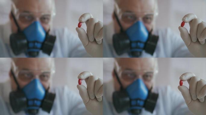 一家制药公司的科学家一名戴着蓝色呼吸器和安全眼镜的药品开发商拿着一种新药一颗红色药丸看着它