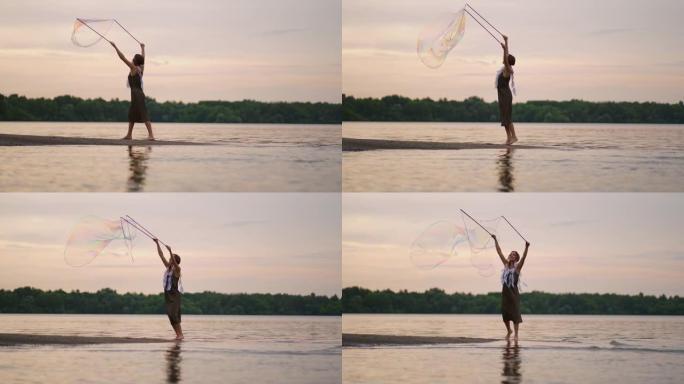 一位年轻的女艺术家展示了一个肥皂泡表演，在日落时在湖岸上吹起巨大的肥皂泡。在慢动作中展示美丽的肥皂泡