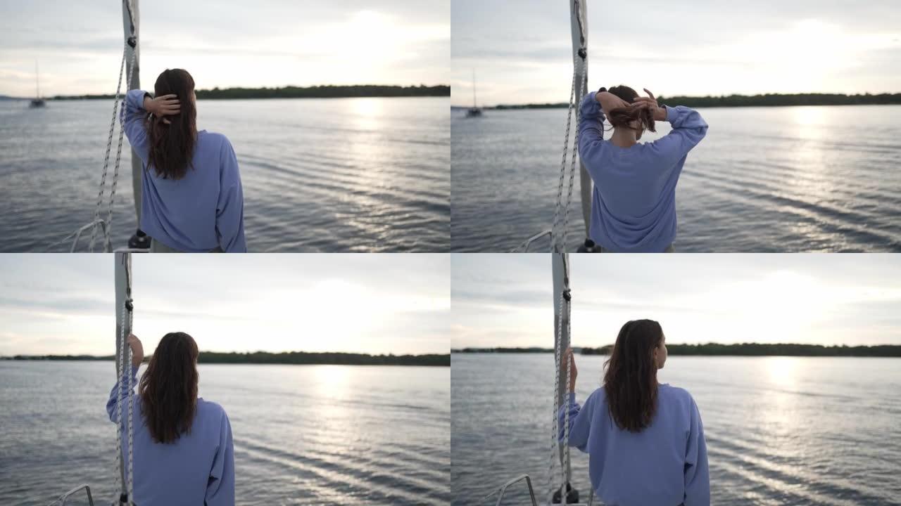 日落时，年轻女子从帆船望向海湾对面