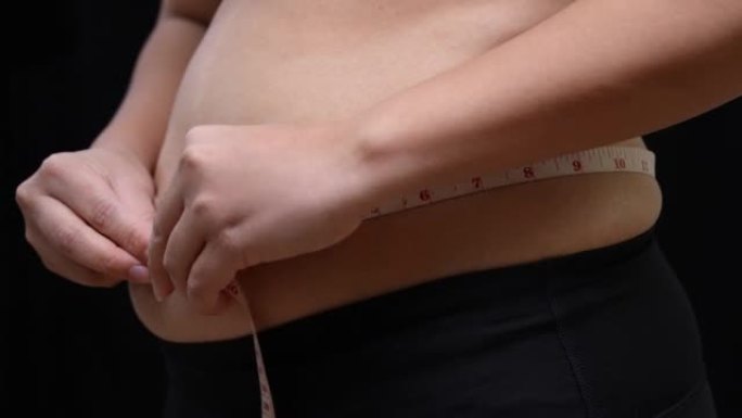 超重的女人测量她的腹部