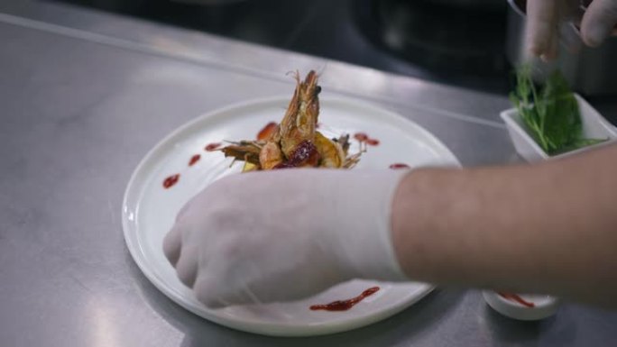 高角度观景盘，熟虾和雄性手在慢动作中加入草莓。无法辨认的高加索男厨师在餐厅厨房装饰食物。