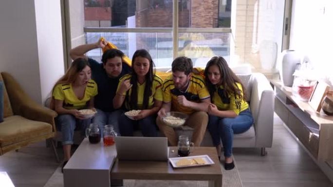 一群在家中的朋友在笔记本电脑上观看足球比赛，非常兴奋和紧张地庆祝得分