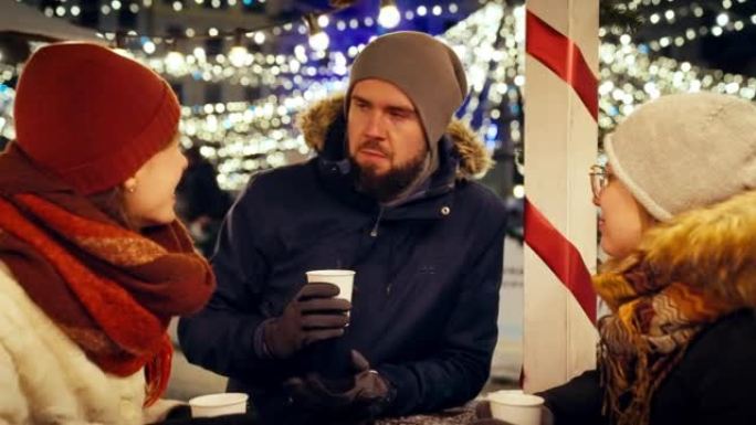 一群朋友在慢动作的下雪的圣诞节夜晚一起喝热巧克力