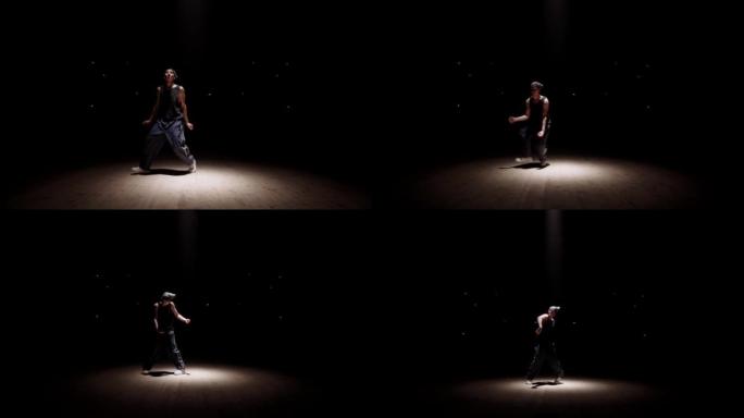 才华横溢的b-boy在黑暗中跳舞，聚光灯下的舞者剪影，活跃而充满活力的舞蹈