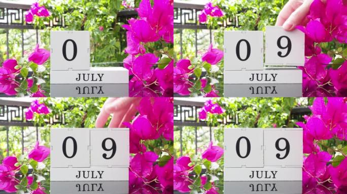 一个木制日历，有一个重要的活动，7月9日在一张有芙蓉花的桌子上，女人的手在日历上设定了日期。将日历翻