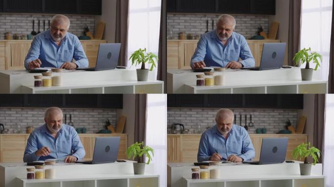 老人正在计算自己的财务状况，坐在家里的厨房里，用计算器计数并在书本上做笔记，使用笔记本电脑