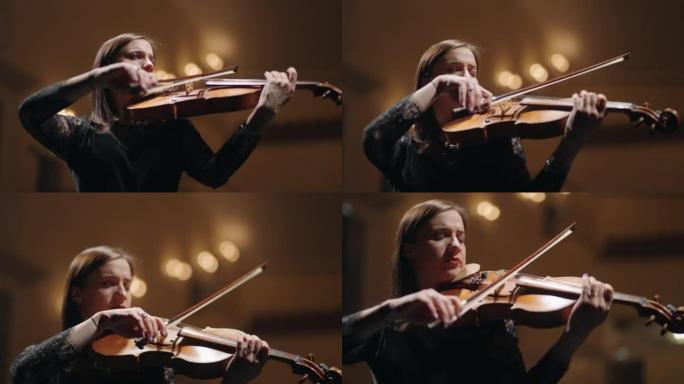 黑衣黑发女郎在爱乐音乐厅演奏小提琴，交响乐团的女音乐家