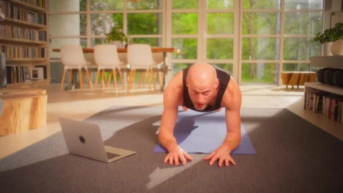 运动员在家庭锻炼时做木板运动。使用笔记本电脑