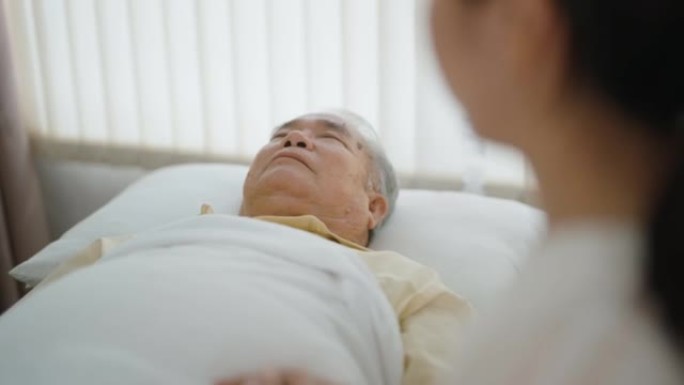 护士躺在病床上照顾高级病人。