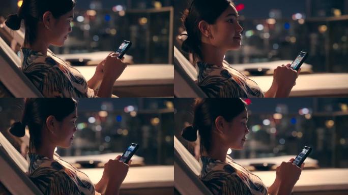 傍晚时分，一名亚裔女子拿着手机坐在高楼的游泳池里，俯瞰着这座城市。