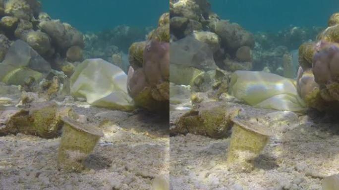 垂直视频:特写。美丽的珊瑚礁上覆盖着塑料垃圾，五颜六色的热带鱼游过这是残骸。海洋塑料污染。