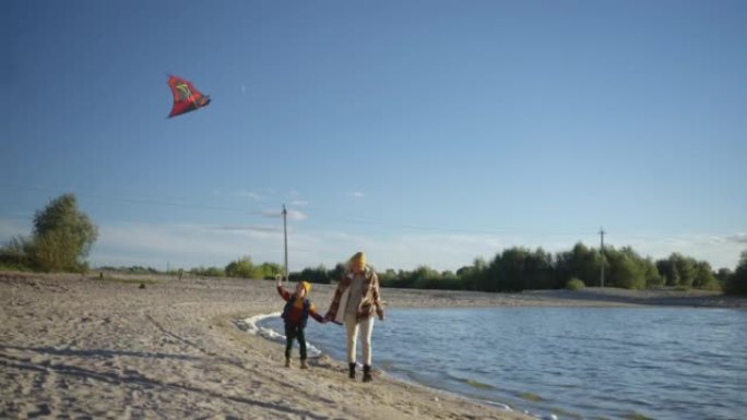 母女俩一起在湖岸刮风的天气里放风筝。家人一起放松