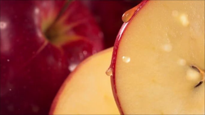 一滴果汁从成熟多汁的红苹果片的表面流下。慢动作4K