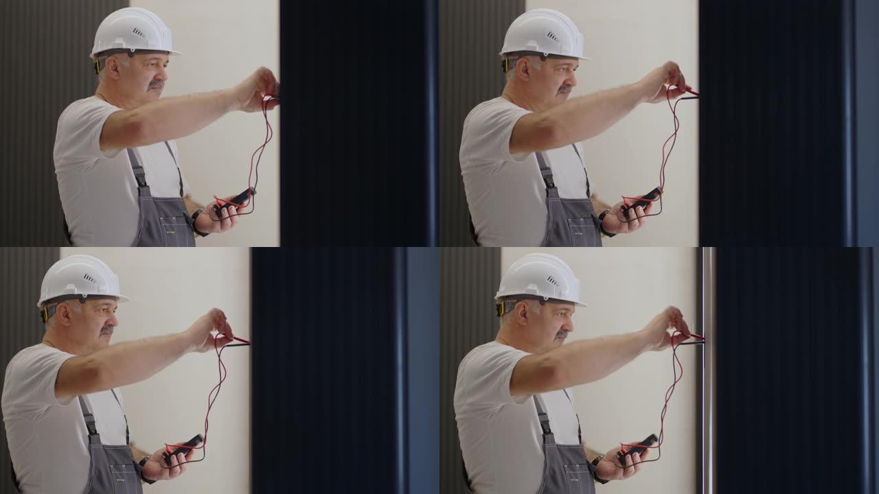 一名男电工用准备安装智能家居的电线测试仪检查网络中的电压。公寓现代内部的电工肖像