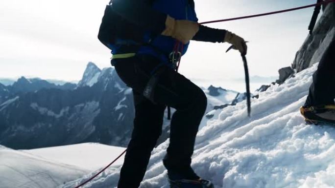 一队登山者在陡峭的山峰上移动。使用绳索和攀爬设备。对着相机做鬼脸