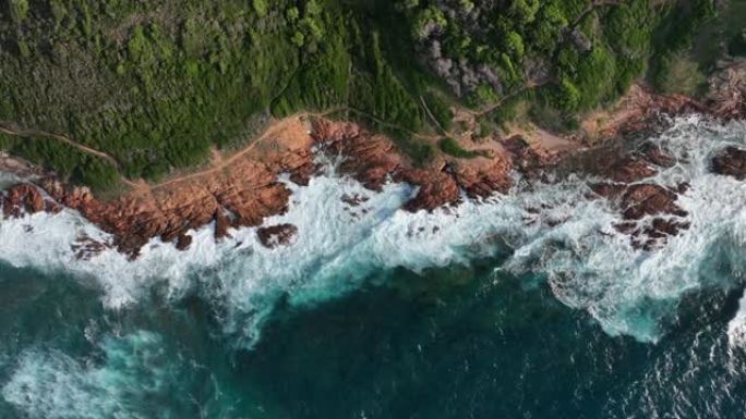 湛蓝海水的鸟瞰图，海浪冲入绿色的草地海岸线