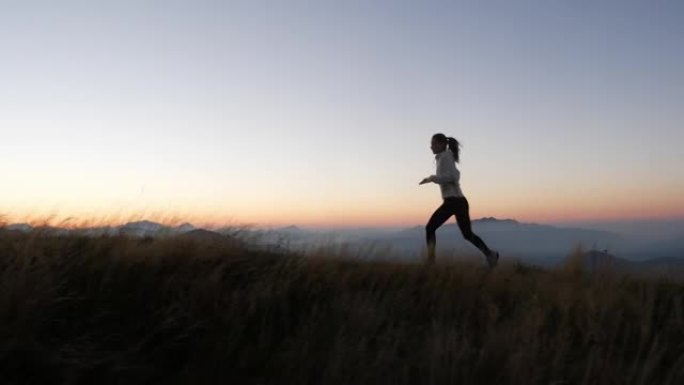在日落时分，一名年轻女子在山上奔跑的镜头之后