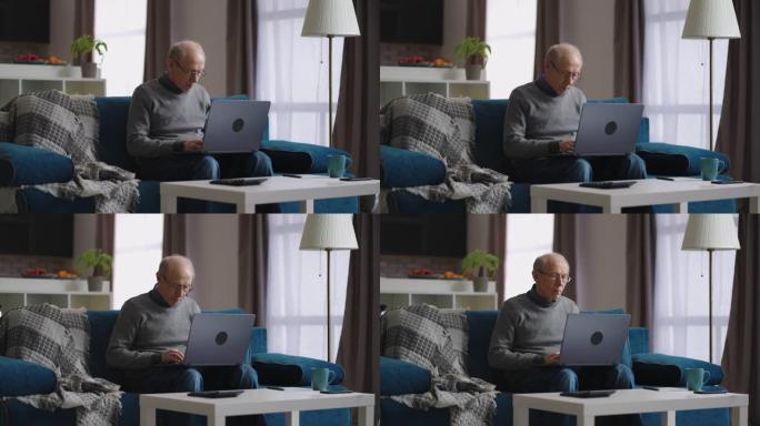 单身退休人员正在家里使用笔记本电脑，在他公寓的客厅里使用老人的肖像，使用现代笔记本电脑