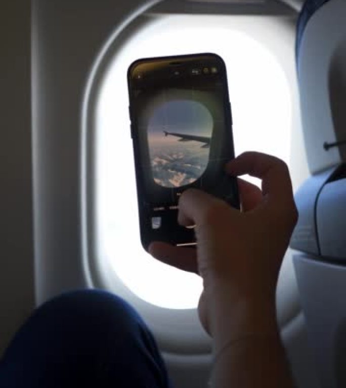乘客在飞机上使用手机拍照的垂直细节照片