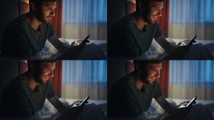 男人在睡觉前使用智能手机，坐在床上，肖像时沉迷于互联网和社交媒体
