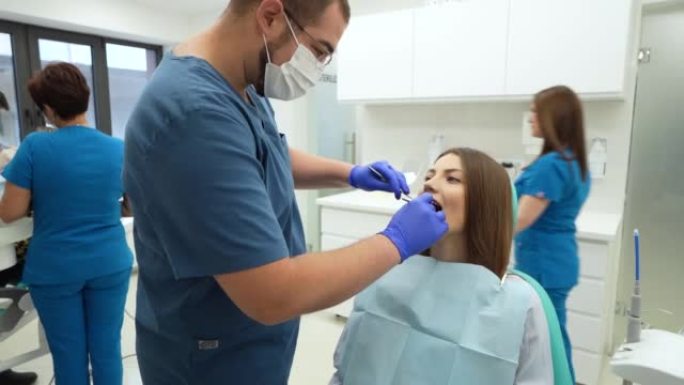 对女性患者进行口腔检查的高加索男性牙医