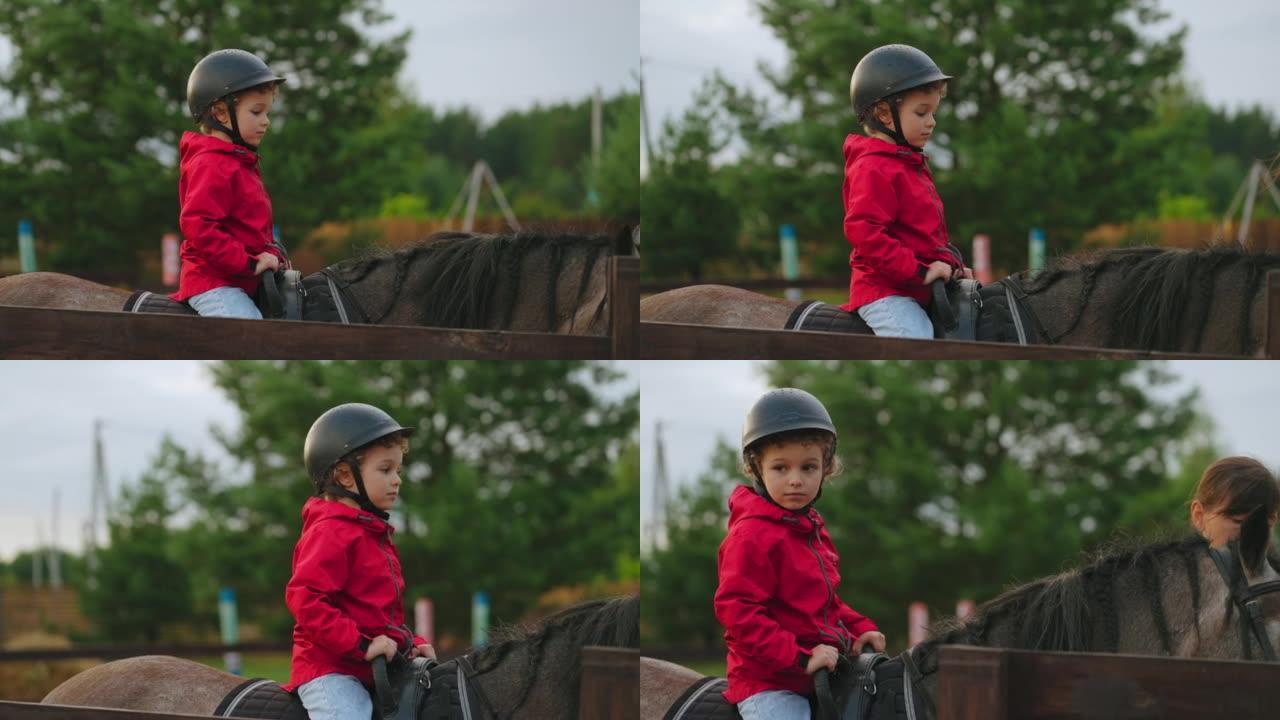 戴着头盔的小男孩坐在小马俱乐部的马背上，为幼儿提供马术课程