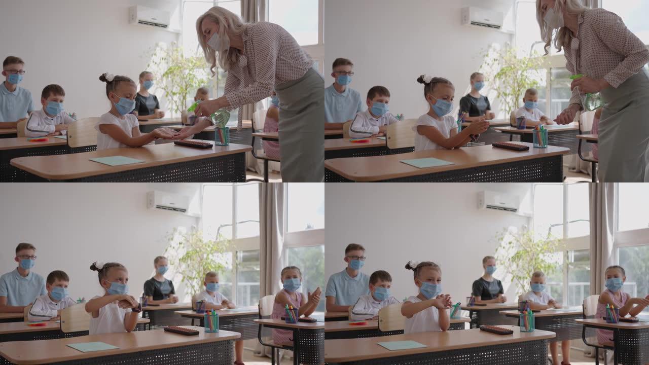 老师上课前在学校的教室里对待一个消毒女孩的手。冠状病毒和学校大流行。流行模式下学校的工作