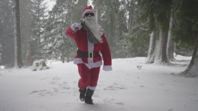 男子打扮成圣诞老人，带着一双滑雪板在白雪皑皑的森林中行走