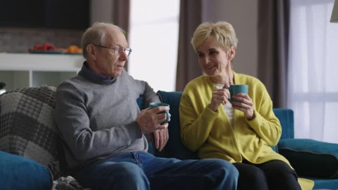 老年配偶周末在家休息，老人和女人坐在客厅的沙发上喝茶