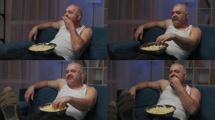 男人嚼爆米花。用左手把一些玉米放进嘴里。