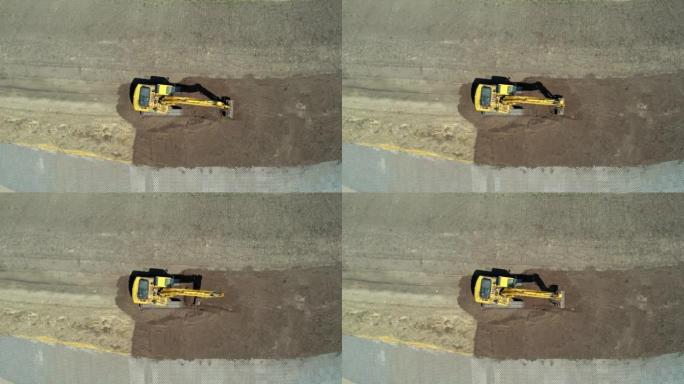 黄色挖掘机，带连续履带。鸟瞰图。高空摄像机。找平挖掘机。施工现场准备。装满挖掘机的铲斗。