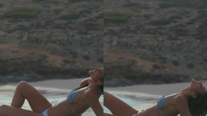 海滩上的女人。在海里玩耍，欣赏海浪垂直视频