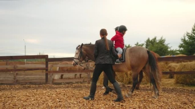 小马俱乐部的儿童海马疗法，小男孩坐在马背上骑马，教练在帮忙