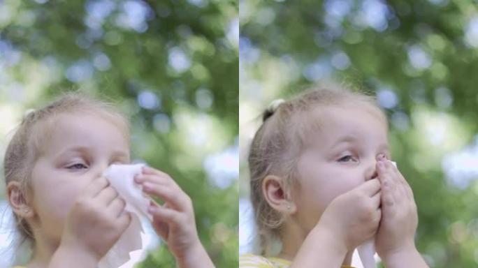 垂直视频: 小女孩用餐巾纸擦脸吃完后，桌上有奶昔。小女孩坐在公园长椅上，用纸巾擦脸的特写镜头。