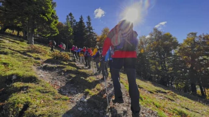 SLO MO POV和一群徒步旅行者一起走在阳光普照的山路上