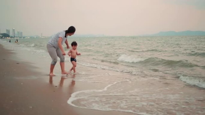 母亲牵着手，小儿子一起在海滩上奔跑。
