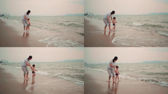 母亲牵着手，小儿子一起在海滩上奔跑。