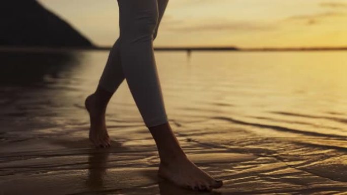 海滨慢跑训练。享受日落和自由的女人。赤脚走在潮湿的沙滩上