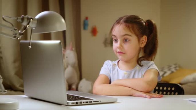 学龄前女孩带着笔记本电脑在家里的在线学校学习。