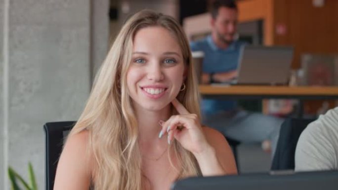 SLO MO年轻女子在工作空间中使用笔记本电脑时微笑
