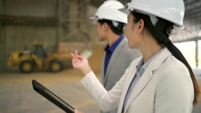 年轻的亚洲企业参观一家大型工厂，用平板电脑谈生意。