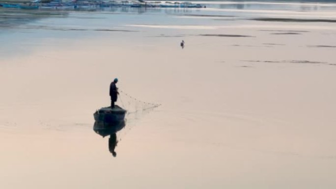一个在湖上钓鱼的农民在早晨的黎明中反射，一个以钓鱼为生的人，一个在湖中央独自钓鱼的人，钓鱼是一种爱好
