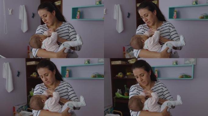 快乐的拉丁美洲母亲在家给戴着髋关节发育不良支架的小女儿喂奶瓶
