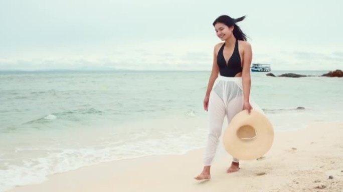 美丽的年轻亚洲女人在海滩上散步。