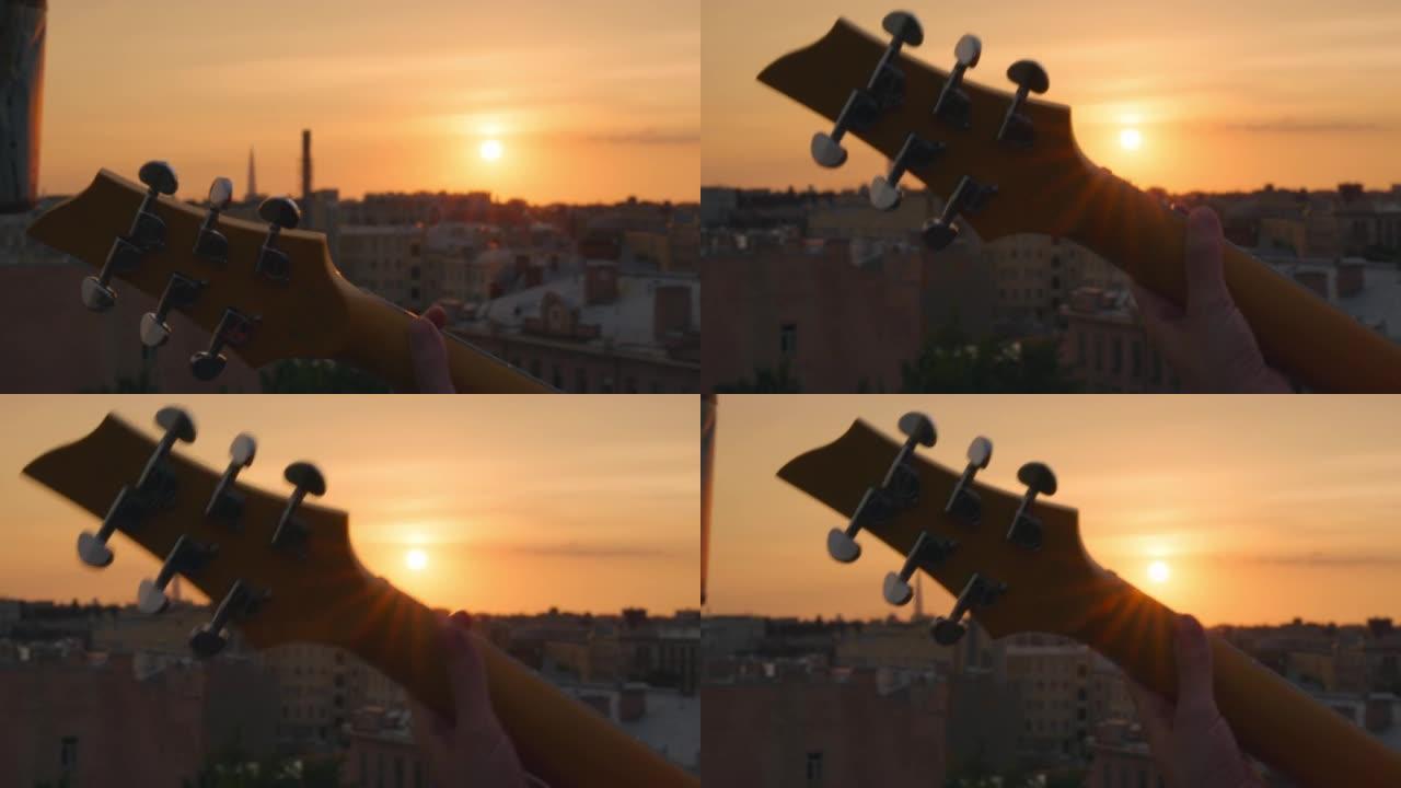 夏季屋顶音乐会上，剪影头颈吉他颈部在五颜六色的日落