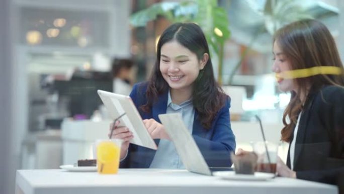 咖啡馆里的两名亚洲商界女性在会议期间微笑着玩得开心。