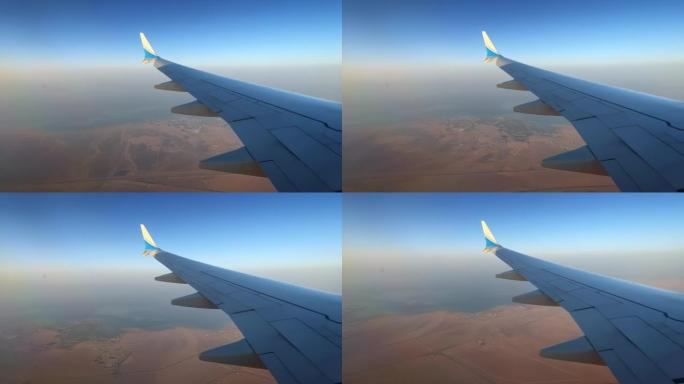 飞机机翼飞越海岸线和干旱的沙漠时光倒流