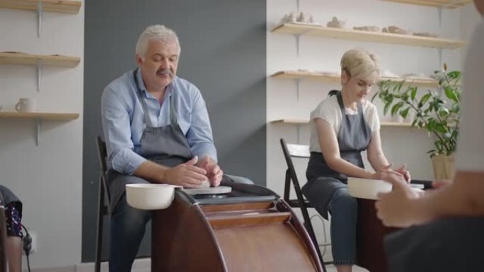 一群高级妇女和一个男人一起学习在陶工的轮子上制作陶器。在退休的陶工轮上制作器皿