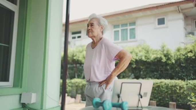 老年妇女看网上健身课在家锻炼