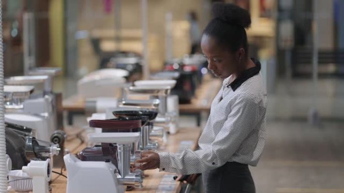 在家电卖场买电动绞肉机，黑人妇女在交易区看样品